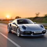 Porsche 911 Turbo S 992 driving at high speed on autobahn during sunrise showcasing supercar performance and stability.