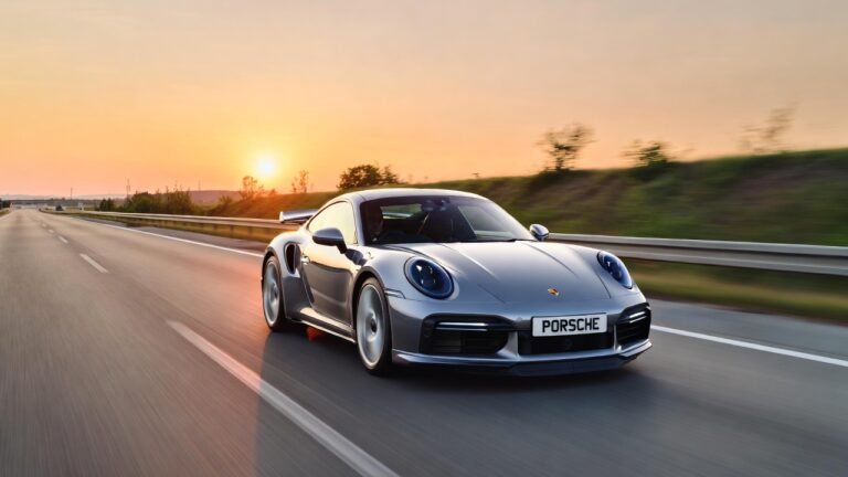 Porsche 911 Turbo S 992 driving at high speed on autobahn during sunrise showcasing supercar performance and stability.